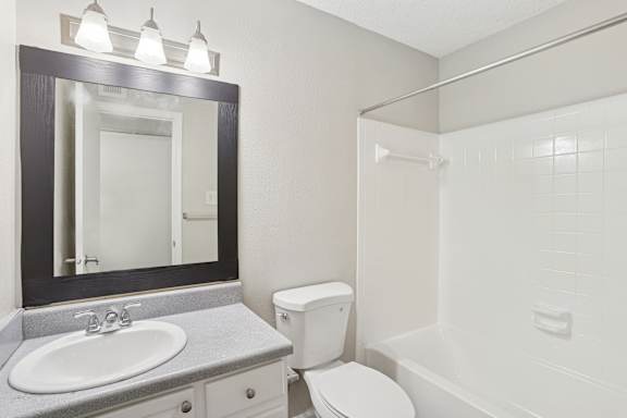 A bathroom with a white toilet, sink, and mirror.