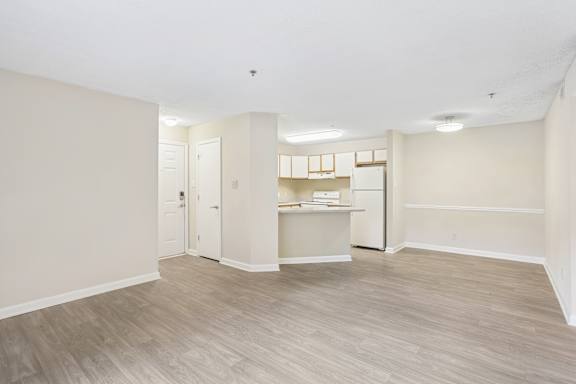 A spacious room with light wood flooring and white walls.