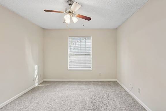 A room with a ceiling fan and a window with blinds.