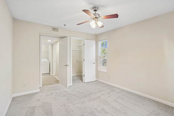 A room with a ceiling fan and carpeted floor.