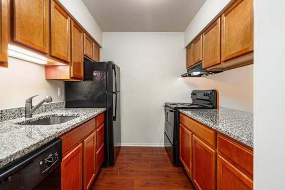 A kitchen with black appliances and wooden cabinets.