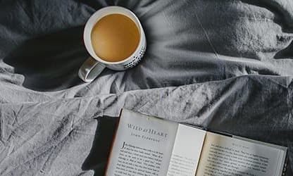 Coffee on bed next to book