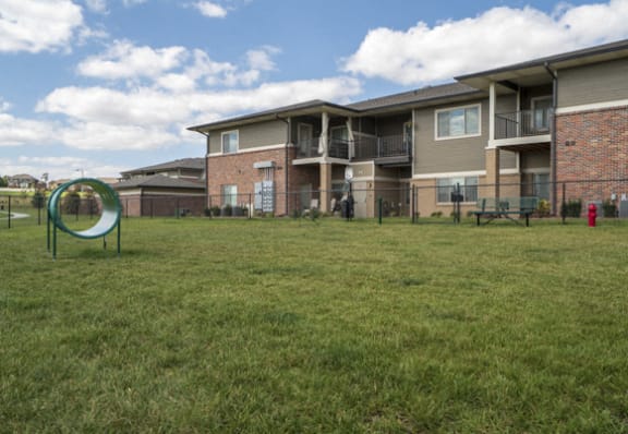 a grassy dog park in front of an apartment building