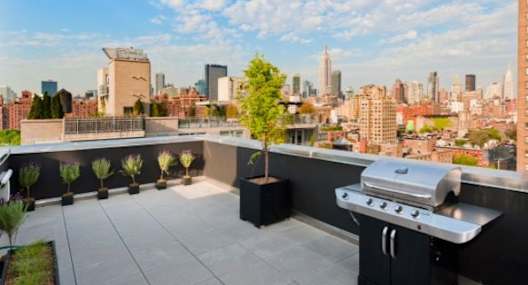a rooftop deck with a grill and a view of the city