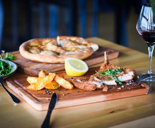 a plate of food and a glass of wine on a table at Emblem Alpharetta, Alpharetta, GA, 30009