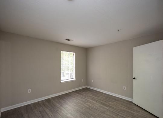 an empty room with wooden floors and a window at Magnolia Pointe Apartments in Duluth, GA