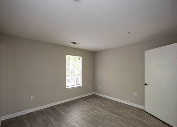 an empty room with wooden floors and a window at Magnolia Pointe Apartments in Duluth, GA