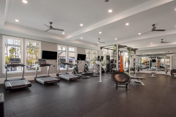 a large fitness room with cardio equipment and windows