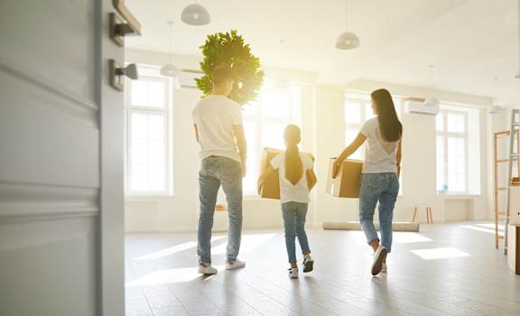 a group of people carrying boxes into an empty house