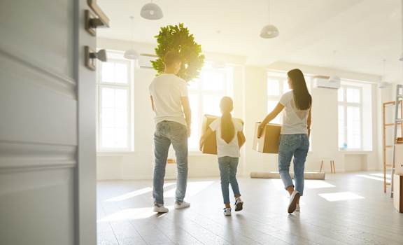 a group of people carrying boxes into an empty house