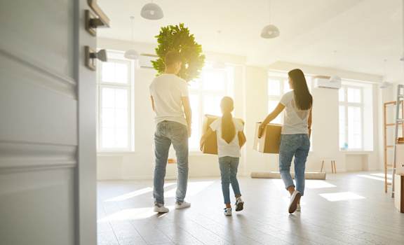 a group of people carrying boxes into an empty house