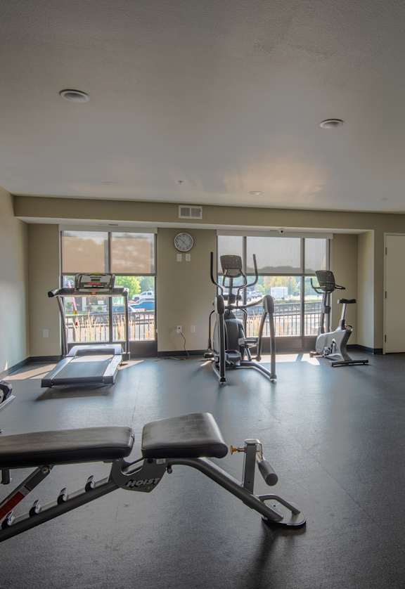 A gym with a variety of equipment including weights, a bench press, and a treadmill.