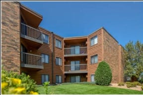 a brick apartment building with balconies and a green yard