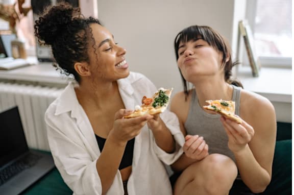 Two women enjoying pizza together in a casual setting.