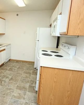 A kitchen with white appliances and wooden cabinets.