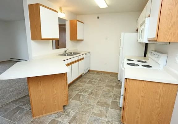 A kitchen with white appliances and wooden cabinets.