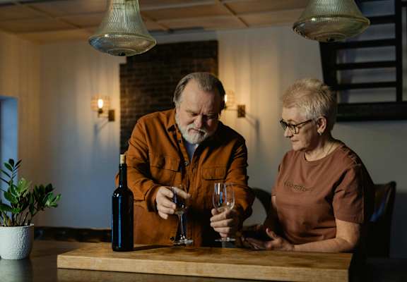 Two people sitting at a table with wine glasses and a bottle of wine.