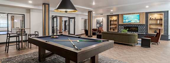 A pool table is in the middle of a room with a fireplace and a TV.