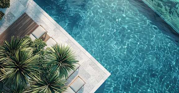 A pool with a wooden deck and palm trees.