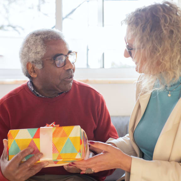an older man and woman exchanging a present