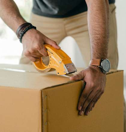 a man cutting a cardboard box with an electric saw