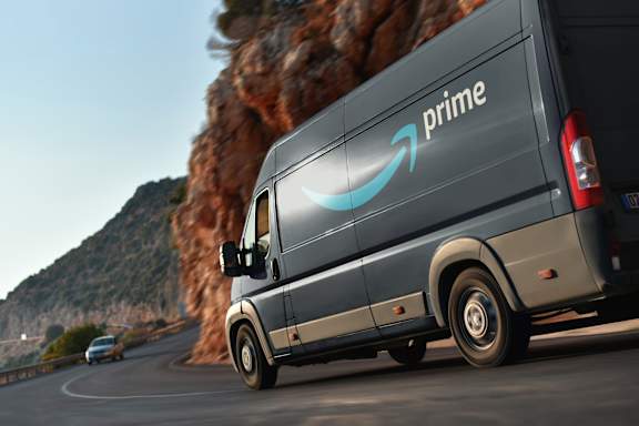A grey Amazon Prime van is driving on a road.