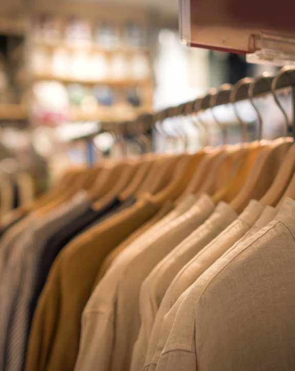 a row of shirts hanging on a rack in a clothing store