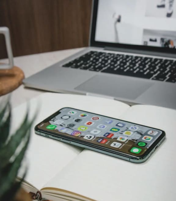 a cell phone sitting on a desk next to a laptop