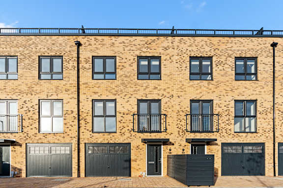 A row of brown brick houses with black garage doors.
