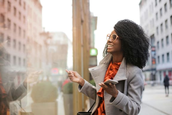 a woman looking out of a window while holding a cell phone