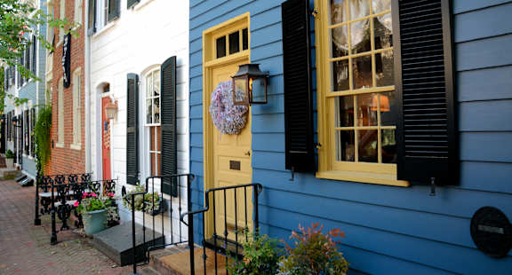 A blue house with a yellow window and a red door.