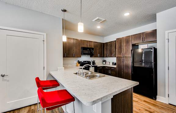 A kitchen with a white counter top and red chairs.