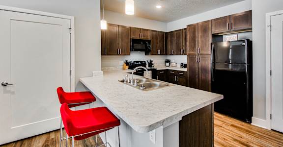 A kitchen with a white counter top and red chairs.