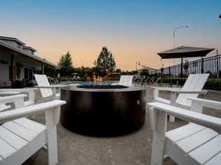 round fire pit with white chairs and benches around it at sunset at Sonder Fields in Happy Valley, OR