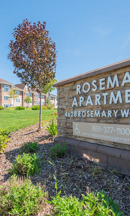 A sign for Rosemary Apartments is in front of a grassy area.