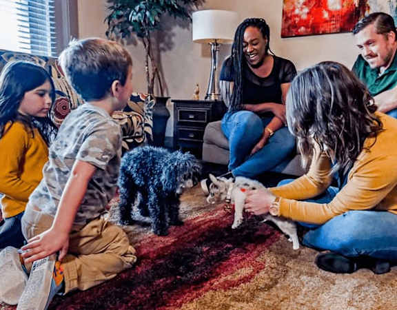 A family is sitting on the floor with their dog.