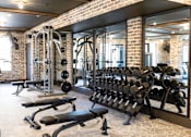 Thumbnail 7 of 9 - A gym with a brick wall and a mirror. at District on the Etowah Apartments, Canton, GA