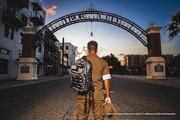 A man in military uniform stands in front of a gate.