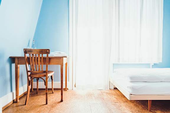 A wooden chair sits in front of a blue wall.