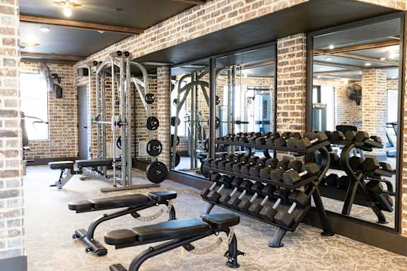 A gym with a brick wall and a mirror. at District on the Etowah Apartments, Canton, GA