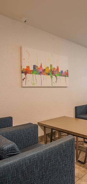 A room with a painting on the wall and a table with chairs.