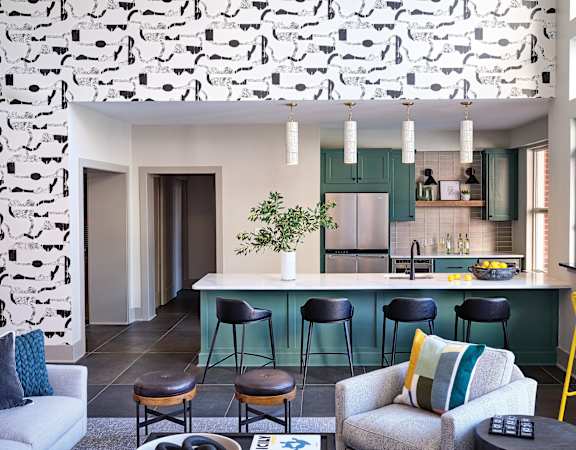 Modern Community Kitchen with Green Cabinetry, Bar Seating, and Lounge Area at Allister North Hills Apartments in Raleigh, NC