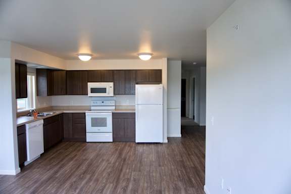 A kitchen with white appliances and brown cabinets.