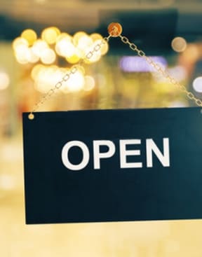 open sign board hanging on the glass door of the shop
