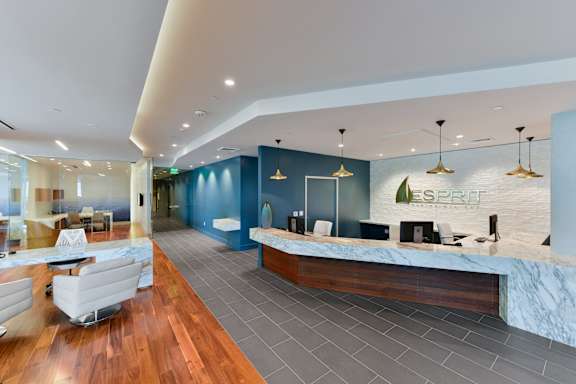 A reception area with a blue wall and a white reception desk. at Esprit Apartments, Marina del Rey, CA, 90292