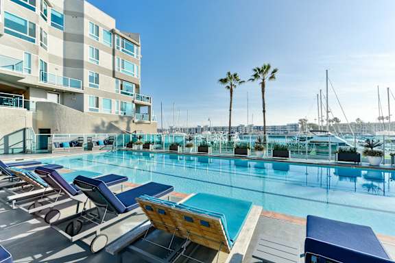 A pool with sun loungers and a building in the background.