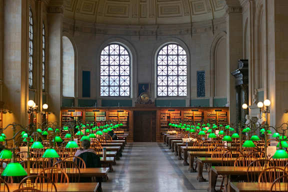 A room with rows of green lampshades and a person sitting in the middle.