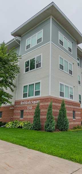 A large apartment building with a red brick base and white upper floors.