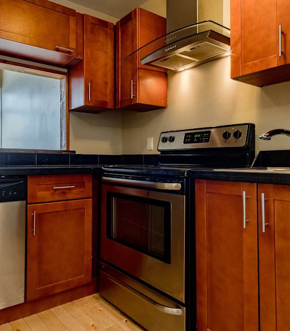 A kitchen with wooden cabinets and black countertops.