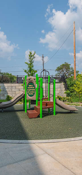 A playground with a green slide and a brown bench.